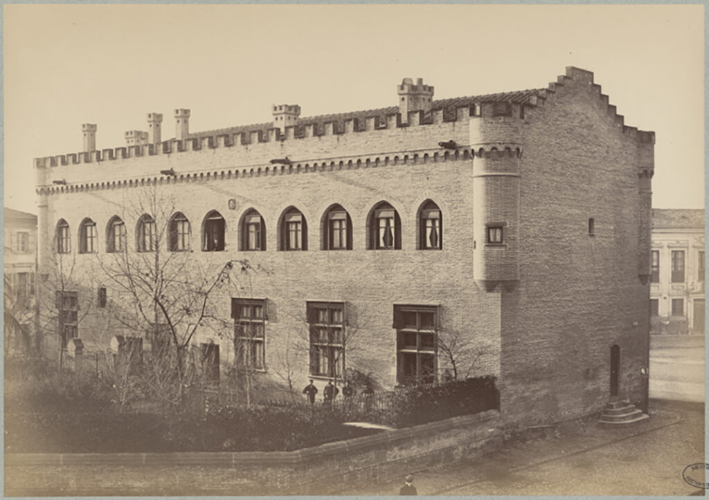 Photographie ancienne du bâtiment qui accueille le musée Saint-Raymond et son jardin. Les cheminées crénelées et le mur pignon en escalier ont disparu. La toiture est aujourd’hui débordante.