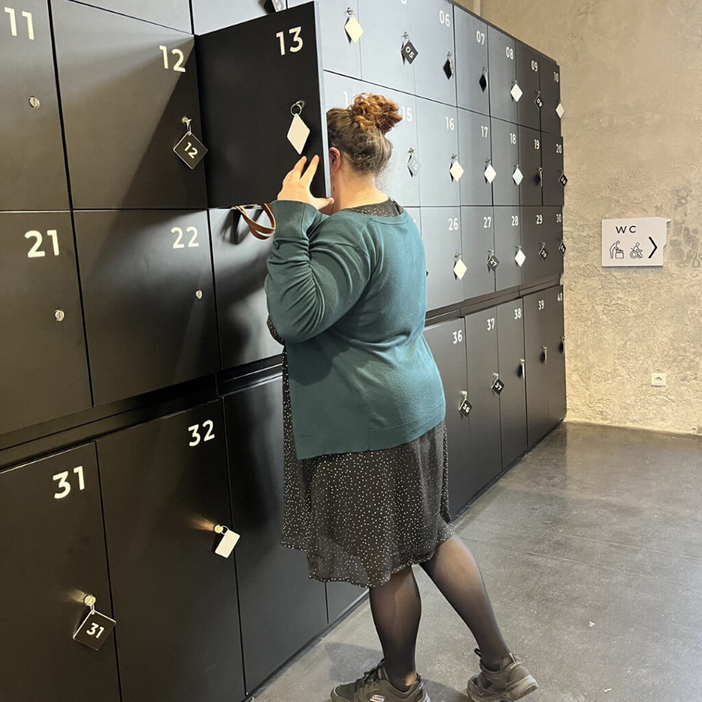 Une visiteuse est en train de placer son sac dans l'un des casiers-consigne