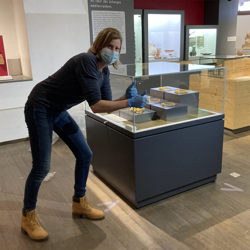 La directrice du musée, devant la vitrine présentant les torques, lève les deux pouces en l'air, satisfaite de sa nouvelle installation.