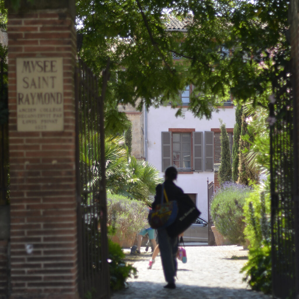 Une personne, de dos, entre dans la cour du musée Saint-Raymond.